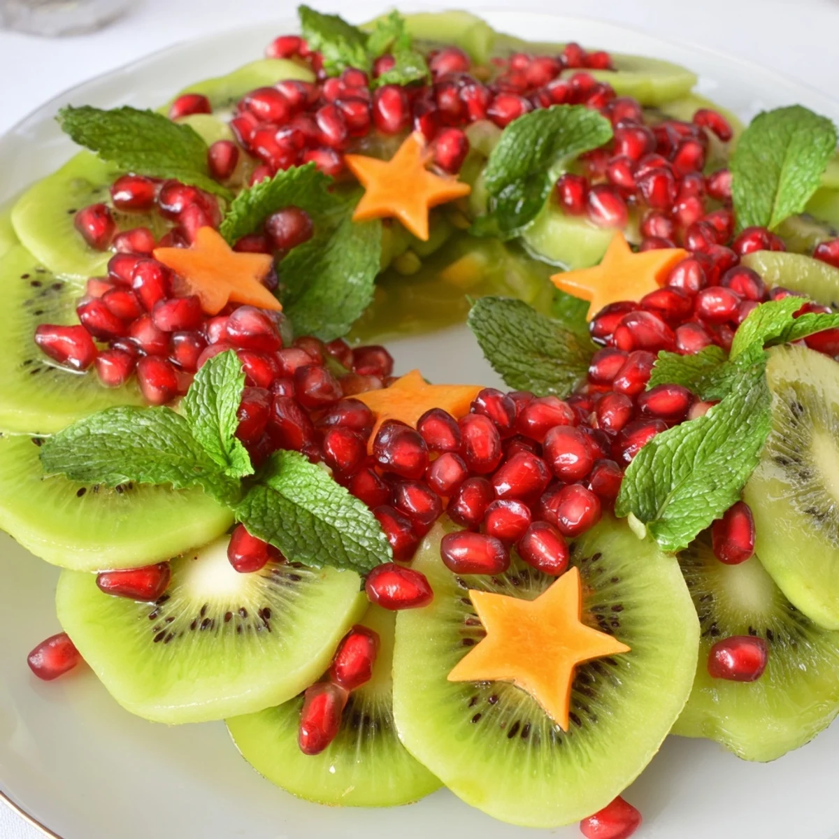Fresh kiwi slices and juicy pomegranate seeds create a beautiful Christmas wreath fruit plate, ready to serve.