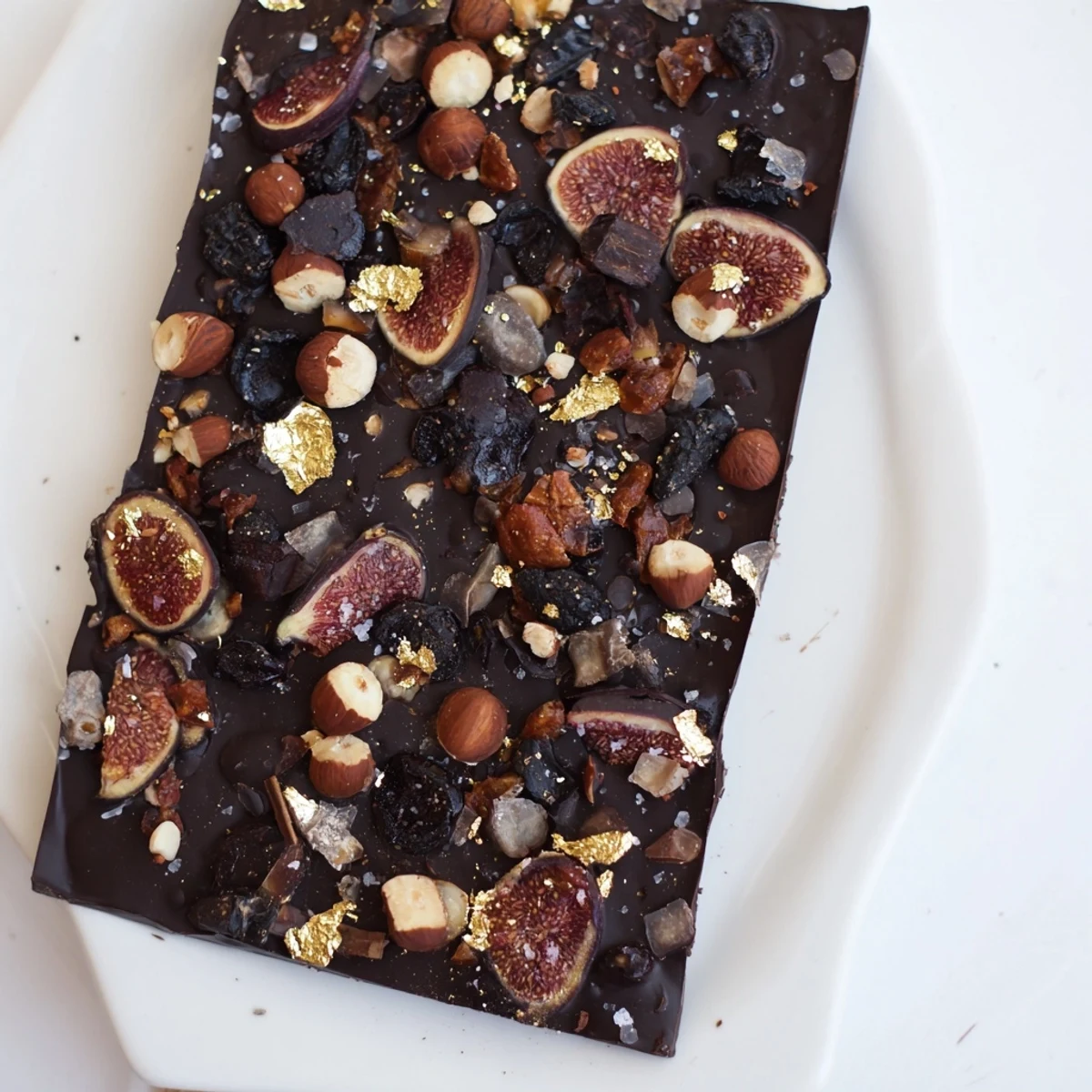 This Midnight Mosaic dessert presents a decadent close-up of dark chocolate adorned with figs and olives.
