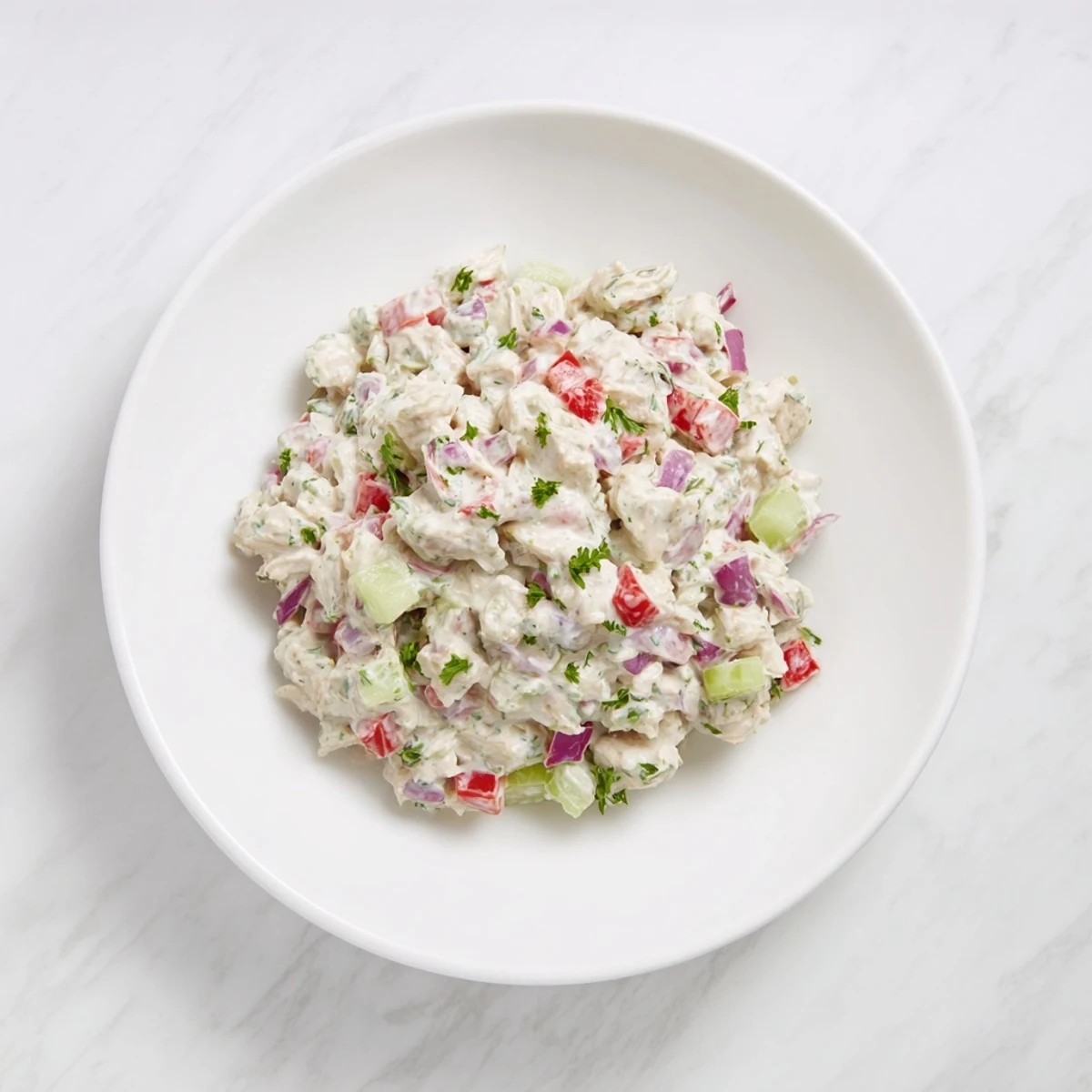 Creamy canned chicken salad with Mrs. Dash, celery, and red peppers, ready to serve on crackers.