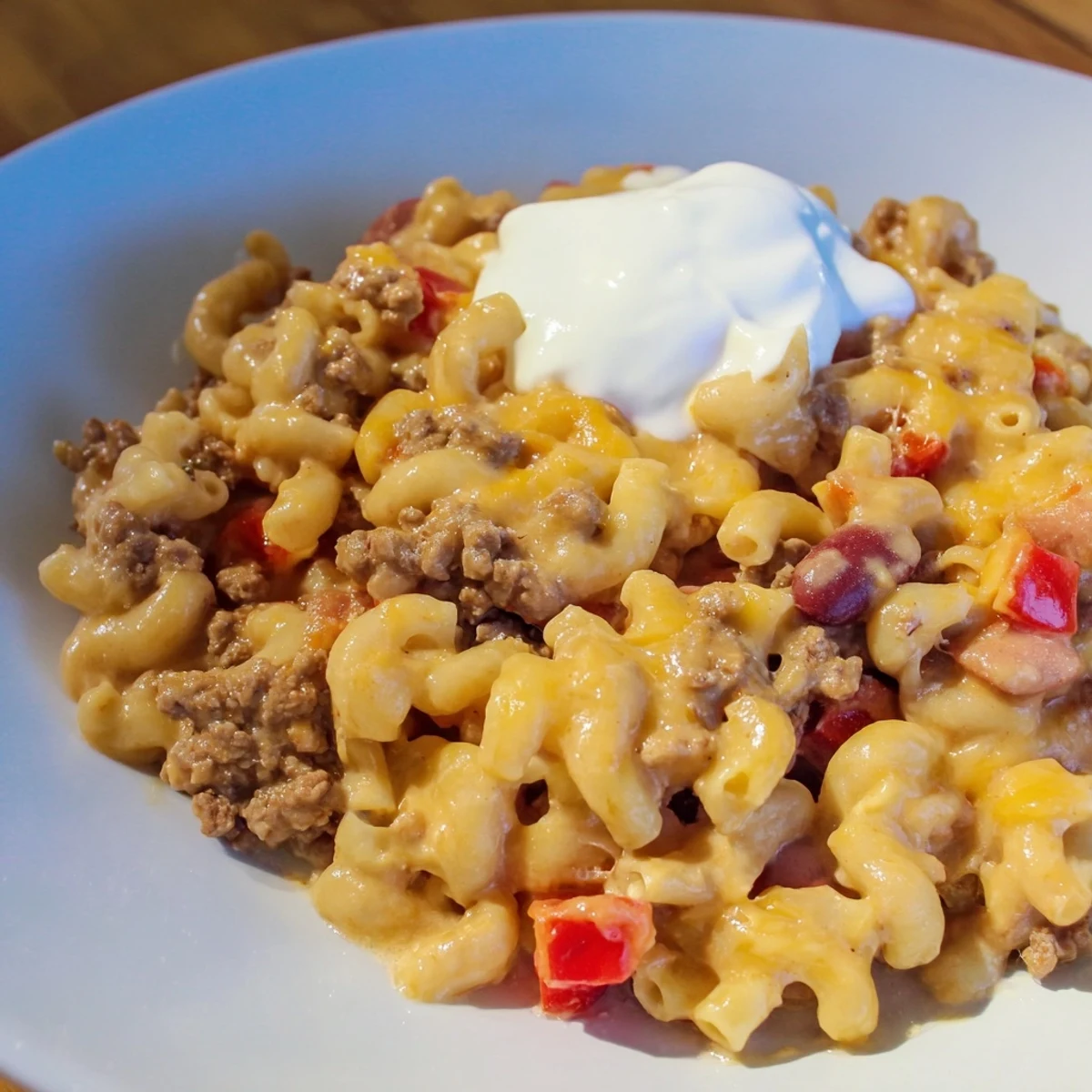Hearty One-Pot Chili Mac, perfect for a chilly evening, topped with melty cheddar cheese and sour cream.