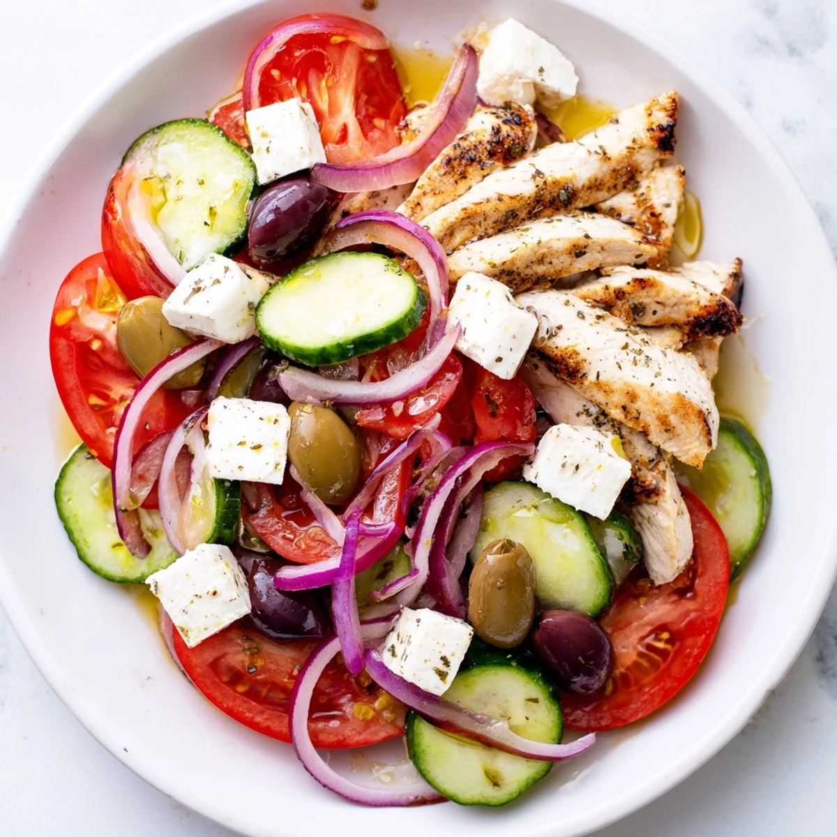 A delicious Mediterranean Greek salad features grilled chicken, olives, and a zesty olive oil dressing.