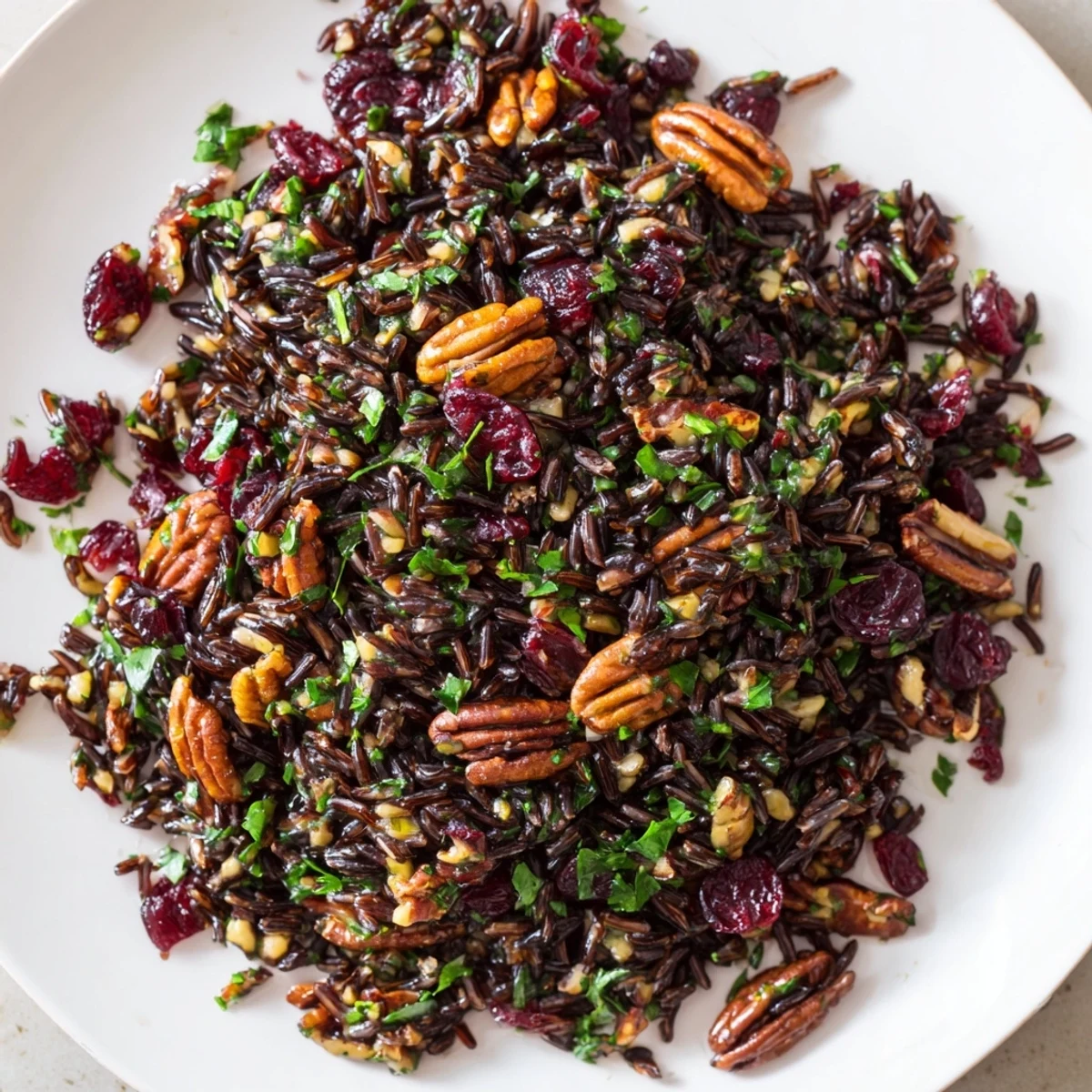 Bowl of Wild Rice Harvest Salad with toasted pecans, dried cranberries, and fresh herbs in a zesty vinaigrette.