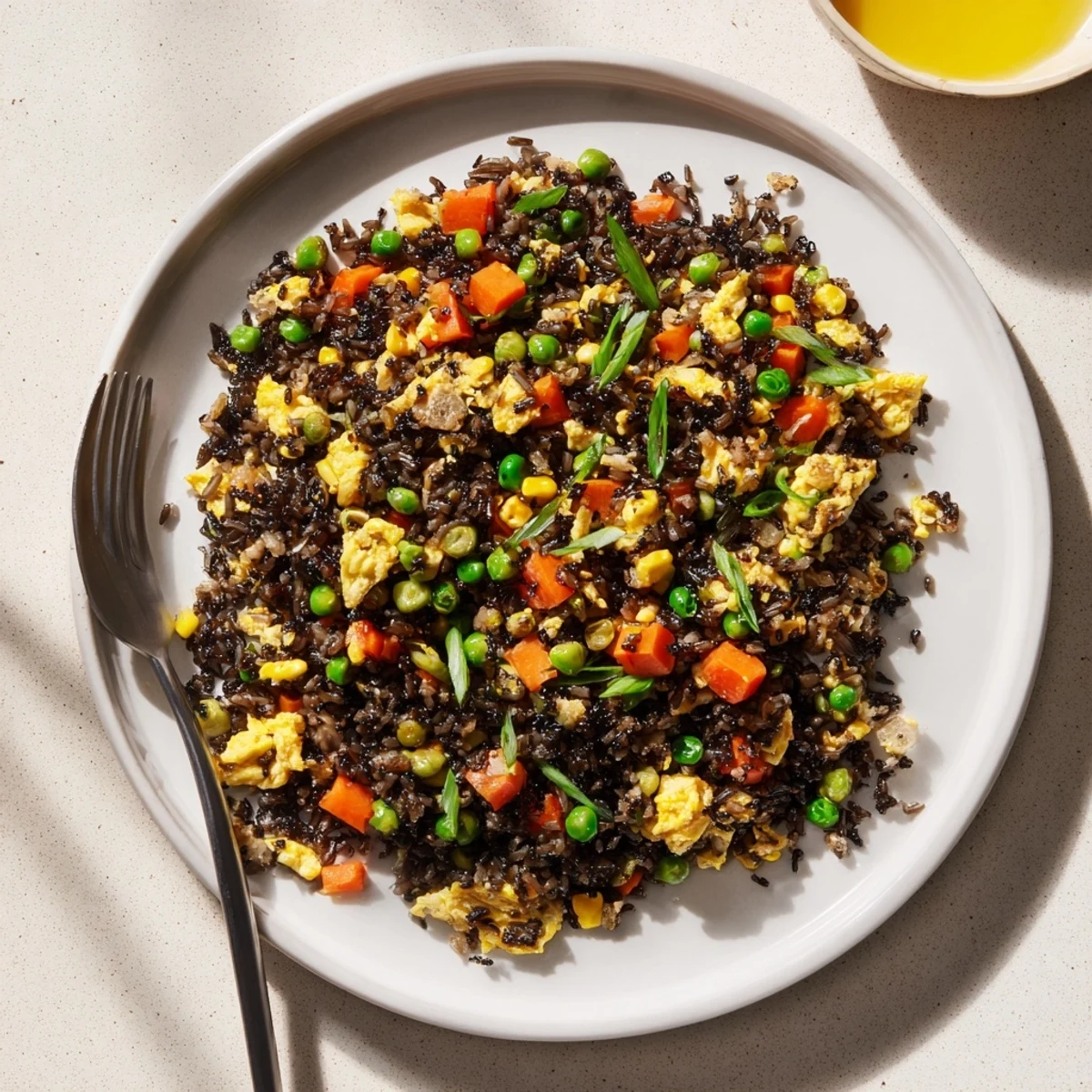 Close-up of Black Garlic Fried Rice with a glossy sauce finish, served alongside a small dish of kimchi for a flavorful bite.