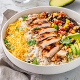 Golden rice forms the base of a colorful Spicy Chicken Burrito Bowl, layered with smoky black beans, sweet corn, and fresh cilantro garnish.  