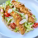 Crispy Chicken Caesar Pita with fresh romaine, shaved Parmesan, and a drizzle of dressing.