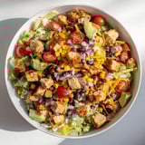 Vibrant Chicken Taco Chopped Salad in a white bowl, featuring black beans, corn, tomatoes, and creamy salsa ranch dressing.