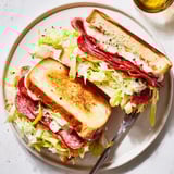 Italian Sub Grilled Cheese sandwich on a plate, topped with tangy lettuce and served with chips.