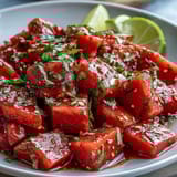 Zesty Tajin-seasoned watermelon wedges with a squeeze of lime create a colorful, refreshing appetizer bursting with flavor.