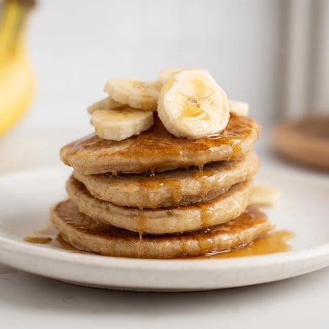 Golden-brunch banana pancakes, stacked high, drizzled with warm maple syrup, perfect for weekend breakfast.