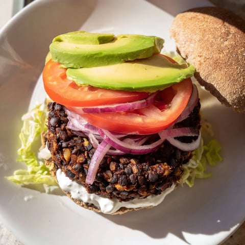 Close-up of a stacked Zesty Weeknight Black Bean Burger, showcasing fresh avocado and vibrant toppings.