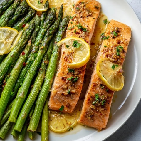 Golden, flaky Skillet Lemon-Butter Salmon with asparagus, glistening with a bright, citrusy sauce for a tasty meal.