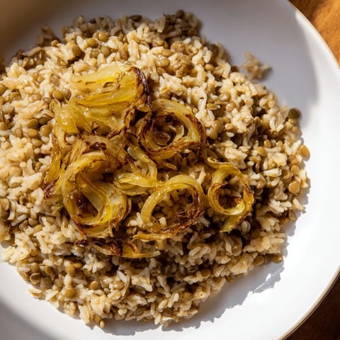 Steaming Lebanese Mjadra, a hearty lentil and rice dish, topped with sweet, golden caramelized onions.