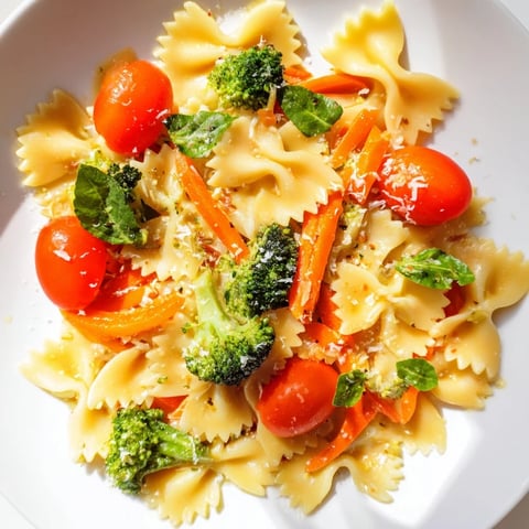 Tossing vibrant bow-tie pasta with fresh spring vegetables like asparagus and cherry tomatoes in a skillet for a rainbow veggie pasta primavera.