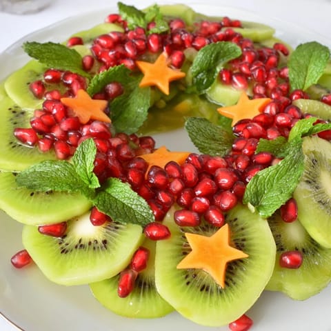Fresh kiwi slices and juicy pomegranate seeds create a beautiful Christmas wreath fruit plate, ready to serve.