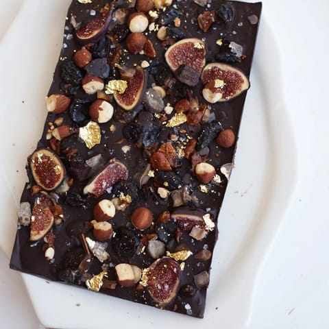 This Midnight Mosaic dessert presents a decadent close-up of dark chocolate adorned with figs and olives.