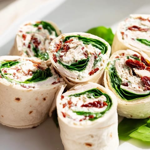 Fresh spinach peeks out of delicious sun-dried tomato turkey roll-ups, a quick and easy recipe.