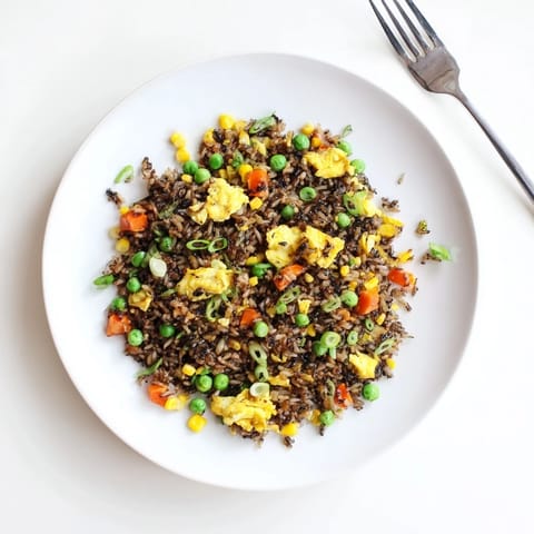 Steaming bowl of homemade Black Garlic Fried Rice featuring tender vegetables and fluffy grains for an easy weeknight dinner.  