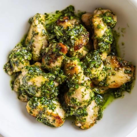 Golden sautéed chicken and bright cherry tomatoes fill a hearty Chicken Pesto Rice Bowl, garnished with toasted pine nuts and a drizzle of basil oil.