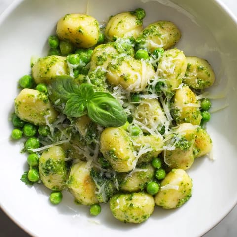 A steaming bowl of Pesto Pea Gnocchi Skillet garnished with Parmesan and lemon zest for a weeknight meal.  
