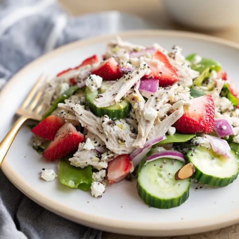 Colorful Strawberry Poppy Seed Chicken Salad served over mixed greens, topped with toasted almonds and optional crumbled feta for a light lunch. 