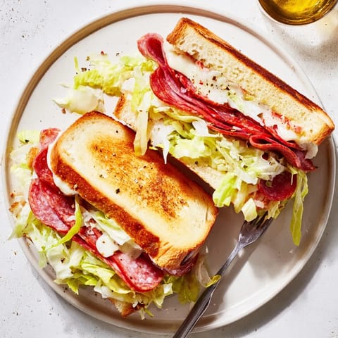 Italian Sub Grilled Cheese sandwich on a plate, topped with tangy lettuce and served with chips.