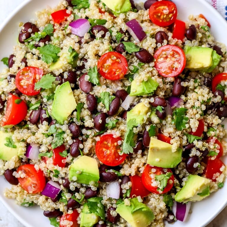 A close-up of a quinoa black bean salad, ready to eat with avocado and fresh cilantro.