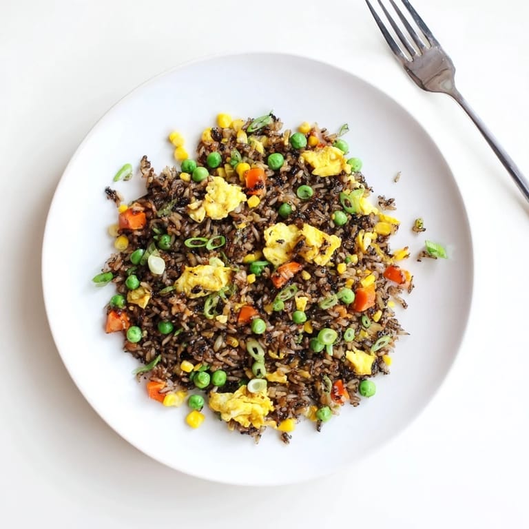 Steaming bowl of homemade Black Garlic Fried Rice featuring tender vegetables and fluffy grains for an easy weeknight dinner.  