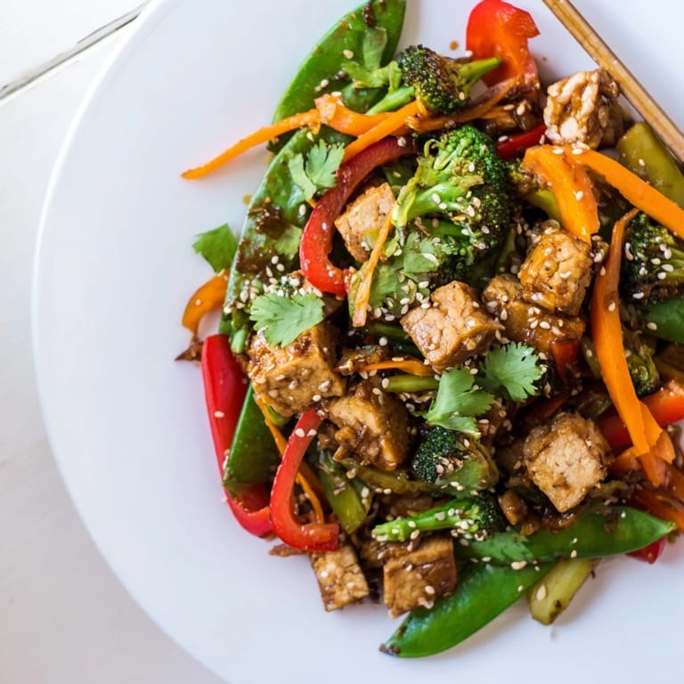 In a wok, a hearty Vegetable Tempeh Stir-Fry showcases bright peppers and tender broccoli tossed with aromatic ginger and garlic.