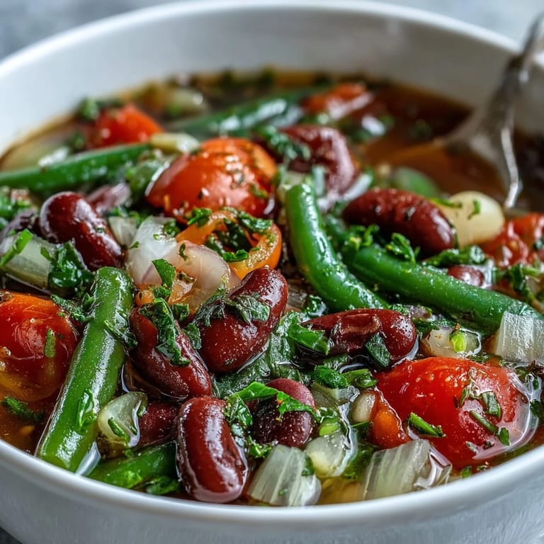 Close-up of Three-Bean Salad Soup garnished with parsley, showing diced red bell peppers and onions for a zesty, hearty meal.