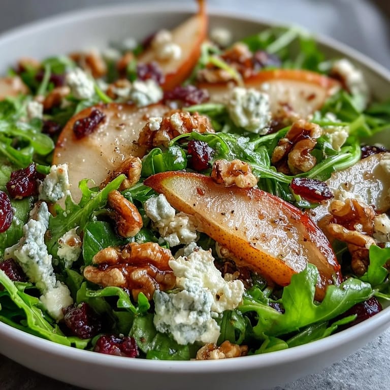 A close-up of the Arugula and Pear Bowl salad with toasted walnuts and a drizzle of balsamic dressing. 
