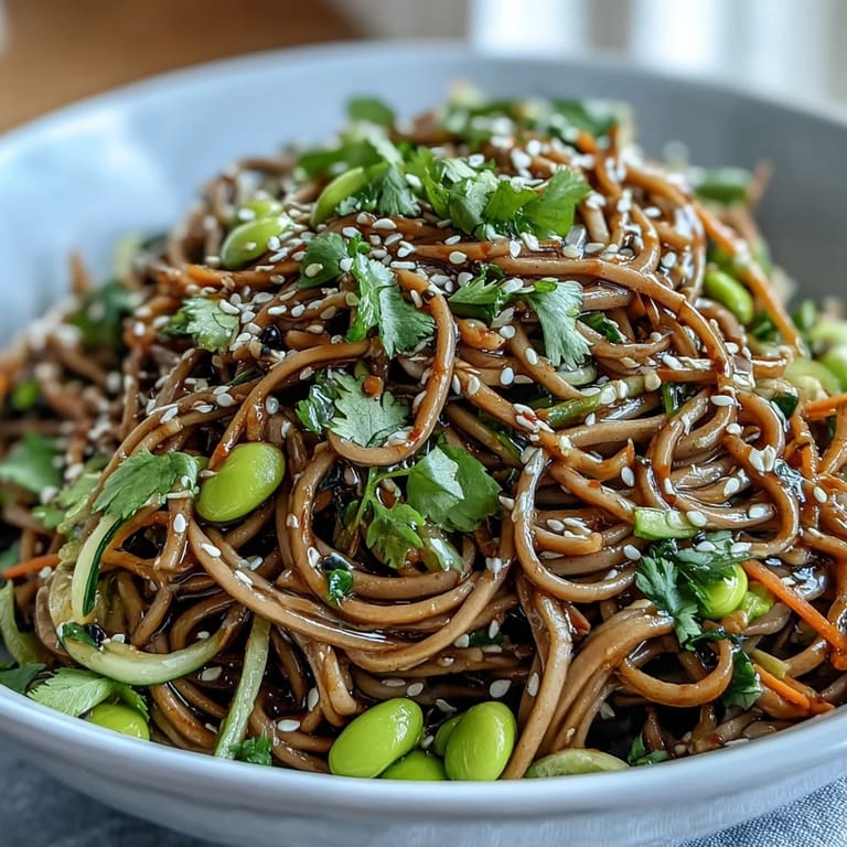 Chilled soba noodle bowl garnished with toasted sesame seeds and scallions, paired with a tall glass of iced green tea for a refreshing lunch.