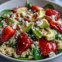 Fresh strawberry avocado quinoa salad with juicy berries, creamy avocado, and zesty citrus dressing in a vibrant bowl.