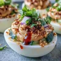 Thai Peanut Deviled Eggs topped with vibrant, fresh cucumber relish.